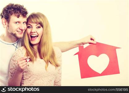 Love romance feelings future marriage home concept. Happy pair holding symbols. Young man and woman presenting keys house cutout with heart pendant.. Happy pair holding symbols.