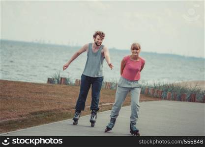 Love romance fitness sport relax leisure active concept. Teens together on skating date. Girl and boy riding together on rollerblades through seafront park.. Teens together on skating date.