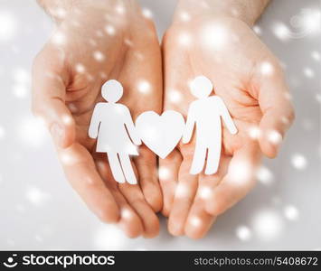 love, romance, safety concept - man hands showing two paper people with heart shape