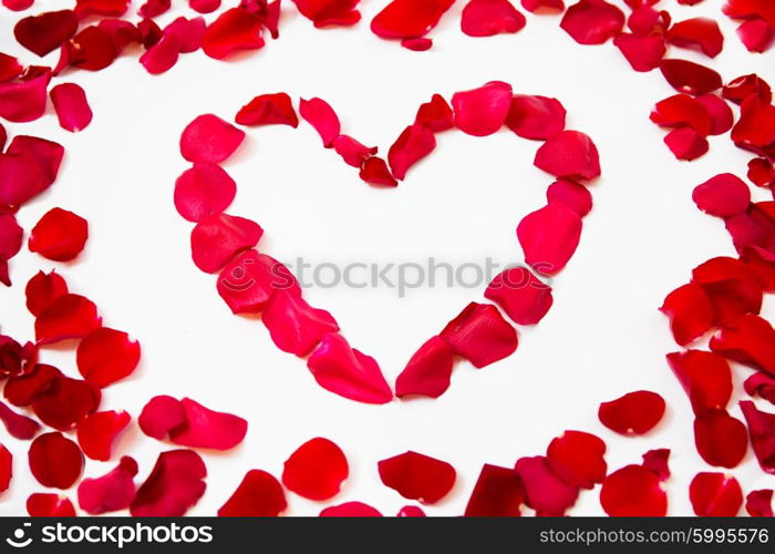 love, romance, valentines day and holidays concept - close up of red rose petals in heart shape