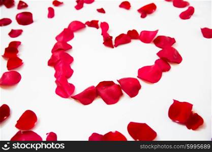 love, romance, valentines day and holidays concept - close up of red rose petals in heart shape