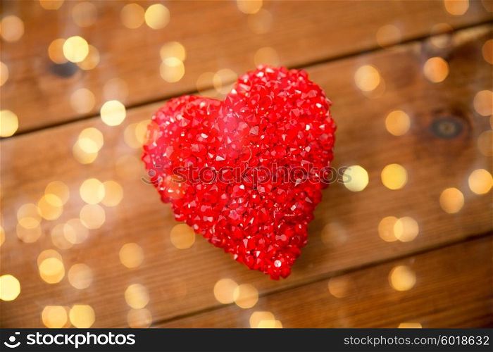 love, romance, valentines day and holidays concept - close up of red heart decoration on wood over lights background