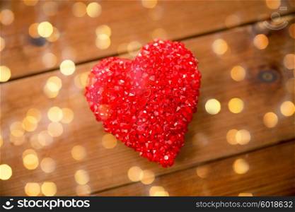 love, romance, valentines day and holidays concept - close up of red heart decoration on wood over lights background