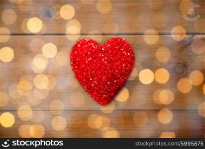love, romance, valentines day and holidays concept - close up of red heart decoration on wood