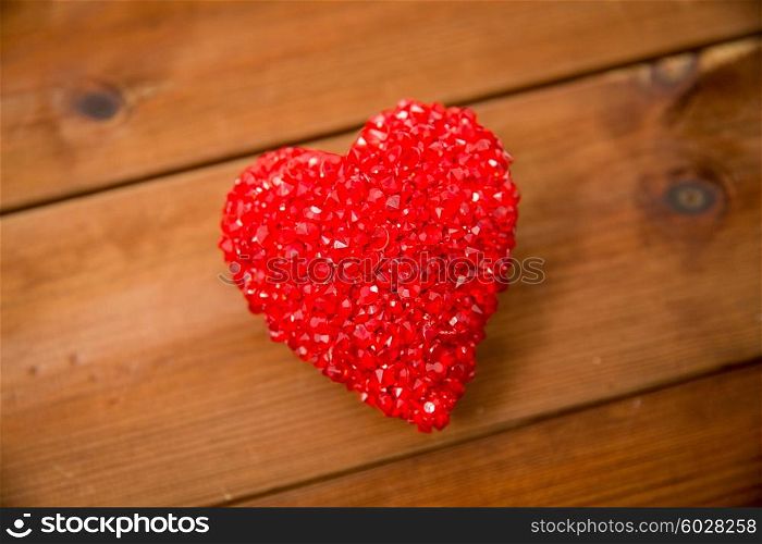 love, romance, valentines day and holidays concept - close up of red heart decoration on wood
