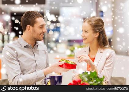 love, romance, valentines day, couple and people concept - happy young couple with red flowers and open gift box in at cafe mall with snow effect