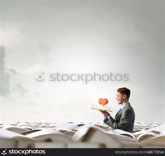 Love science. Young man in pile of books with one in hand