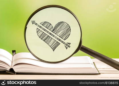 Love search with a pencil drawing of a heart with an arrow in a magnifying glass