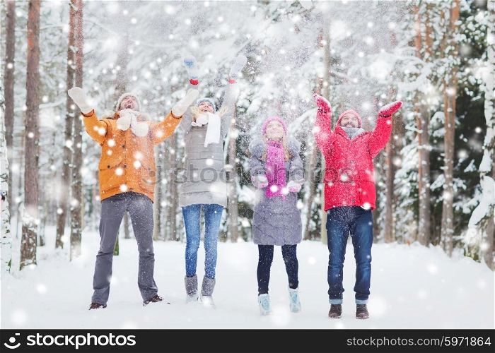 love, season, friendship and people concept - group of happy men and women having fun and playing with snow in winter forest