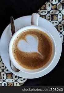 Love shape in a cup of coffee with natural sunlight