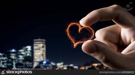 Love sign between fingers. Close view of male hand taking with fingers glowing love symbol
