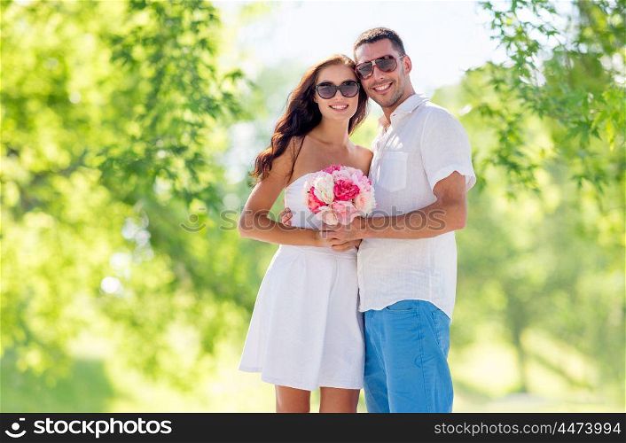 love, summer and relationships concept - happy smiling couple with bunch of flowers hugging over green natural background. happy couple with bunch of flowers hugging. happy couple with bunch of flowers hugging