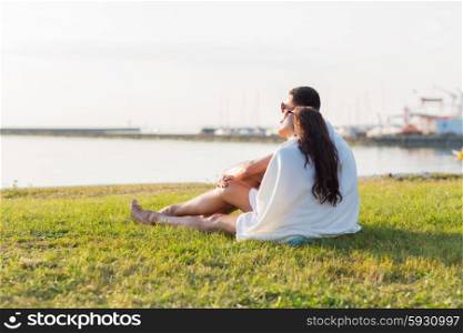 love, summer, dating and people concept - close up of happy couple sitting on grass at seaside