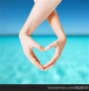 love, summer holidays and vacation concept - close up of woman and man hands showing heart shape