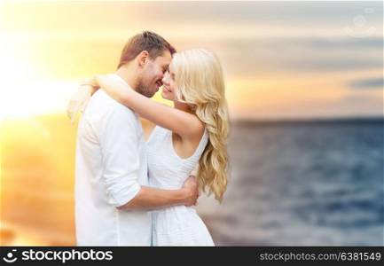 love, summer holidays, relationships and people concept - happy couple hugging over sea background. happy couple hugging and kissing on summer beach