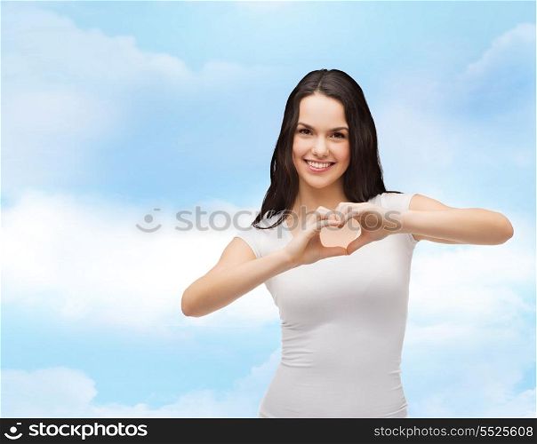 love, t-shirt design and happy people concept - smiling girl in white blank t-shirts showing heart with hands