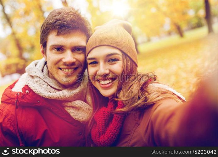 love, technology, relationship, family and people concept - happy smiling young couple taking selfie in autumn park. happy young couple taking selfie in autumn park