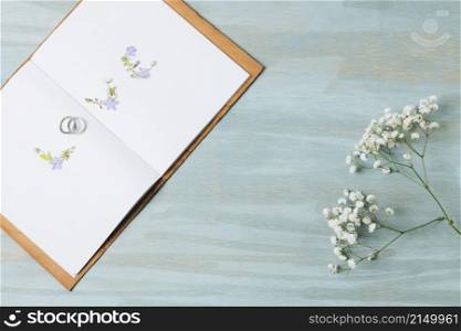 love text made with wedding rings open book with gypsophila flower wooden backdrop