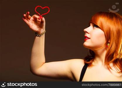 Love to candy and sweets. Valentine&#39;s Day concept. Gorgeous young woman holding candy heart on brown background in studio.