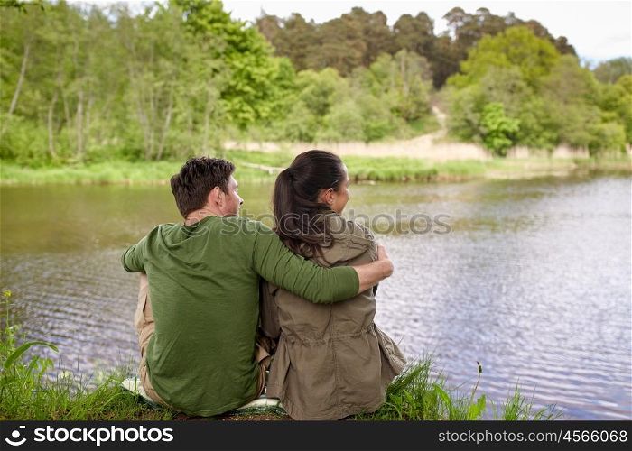 love, travel, hiking, tourism and people concept - happy couple hugging and enjoying natural view on lake or river bank
