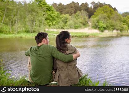 love, travel, hiking, tourism and people concept - happy couple hugging and enjoying natural view on lake or river bank