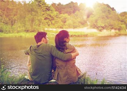 love, travel, hiking, tourism and people concept - happy couple hugging and enjoying natural view on lake or river bank. happy couple hugging on lake or river bank