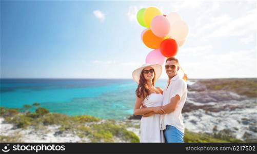 love, travel, summer, relations and people concept - smiling couple wearing sunglasses with balloons hugging over exotic tropical beach and sea background