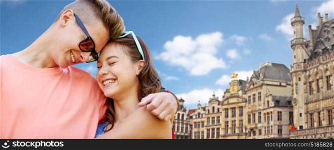 love, travel, tourism and people concept - happy smiling teenage couple hugging over grand place in brussels city background. happy teenage couple hugging in brussels city