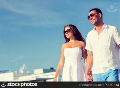 love, travel, tourism and people concept - smiling couple wearing sunglasses and walking in city