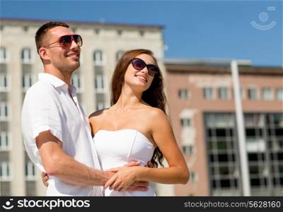love, travel, tourism, people and friendship concept - smiling couple wearing sunglasses hugging in city
