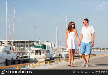 love, travel, tourism, sailing, people and friendship concept - smiling couple wearing sunglasses walking at harbor