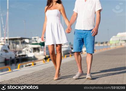 love, travel, tourism, summer and people concept - close up of couple holding hands and walking along waterfront