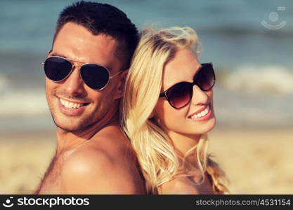 love, travel, tourism, summer and people concept - smiling couple on vacation in swimwear sitting on beach back to back