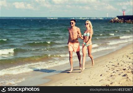love, travel, tourism, summer and people concept - smiling couple on vacation in swimwear and sunglasses holding hands and running on beach
