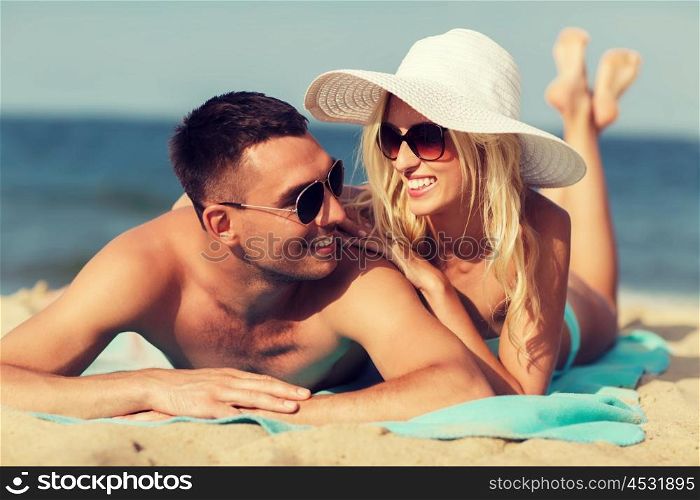 love, travel, tourism, summer and people concept - smiling couple on vacation in swimwear and sunglasses sunbathing on beach
