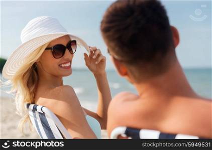 love, travel, tourism, summer and people concept - smiling couple on vacation sunbathing on beach