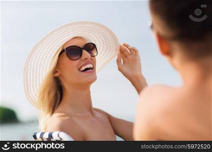 love, travel, tourism, summer and people concept - smiling couple on vacation sunbathing on beach