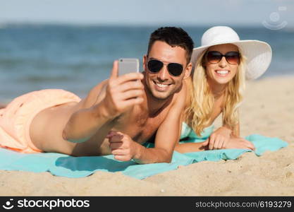 love, travel, tourism, technology and people concept - smiling couple on vacation in swimwear and sunglasses and taking selfie with smartphone on summer beach