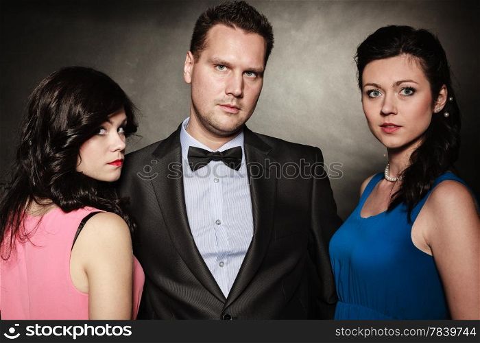 Love triangle. Portrait of two women and one man wearing elegant clothes on black. Mistress and betrayal within the family. Choice before wedding. Luxury party.