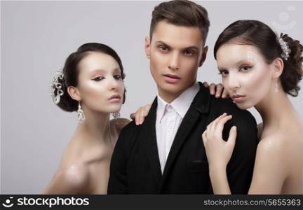 Love Triangle. Two Charming Women Hugging a Handsome Man