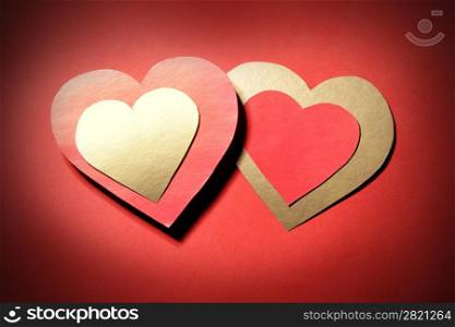 Love - two paper hearts over red background
