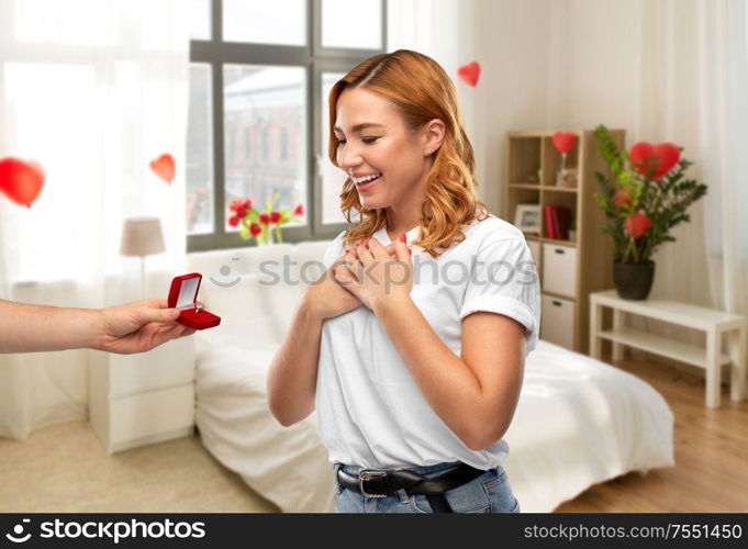 love, valentine&rsquo;s day and proposal concept - man giving diamond engagement ring in little red box to happy woman over home bedroom decorated with heart shaped balloons background. man giving woman engagement ring on valentines day