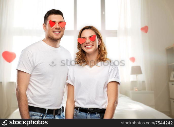 love, valentine&rsquo;s day and relationships concept - smiling couple with red hearts instead of eyes over bedroom decorated with heart shaped balloons background. happy couple with red hearts instead of eyes