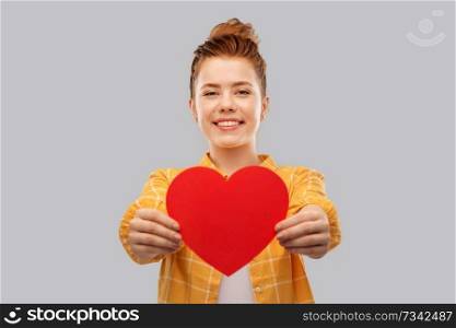 love, valentine’s day and charity concept - smiling red haired teenage girl in checkered shirt with heart over grey background. smiling red haired teenage girl with heart