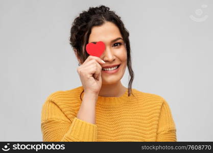 love, valentines day and charity concept - portrait of happy smiling young woman with red heart over grey background. happy smiling young woman with red heart