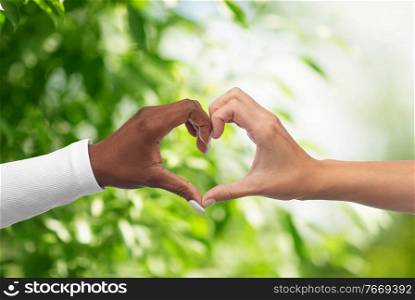 love, valentines day and friendship concept - black and white hands making heart gesture over green natural background. black and white hands making heart gesture