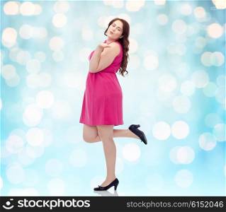 love, valentines day and people concept - happy young plus size woman posing in pink dress and sending blow kiss background over blue holidays lights background