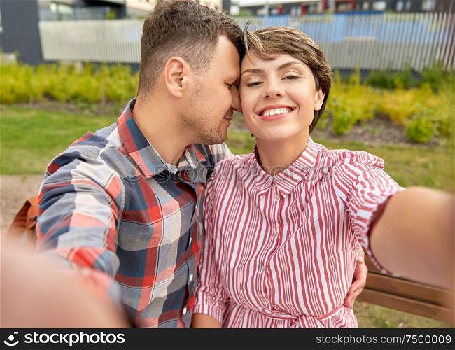 love, valentines day and relationships concept - happy couple in summer park taking selfie outdoors. happy couple in park taking selfie outdoors