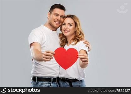 love, valentines day and relationships concept - smiling couple holding big red heart over grey background. smiling couple holding big red heart