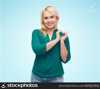 love, valentines day, gesture, plus size and people concept - smiling young woman in shirt and jeans showing heart shape hand sign over blue background